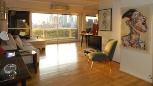 A spacious living room with a city view, a flat-screen TV, a sofa, and a dining area. - Outstanding apartment with amazing views in heart of Palermo verde (Buenos Aires)