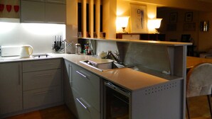 A modern kitchen with grey cabinets, a built-in dishwasher, and a countertop with various kitchen items. - Outstanding apartment with amazing views in heart of Palermo verde (Buenos Aires)