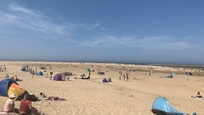 Ein Strand mit Zelten und Menschen.