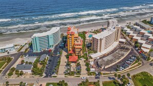 Un hotel frente al mar con varias edificaciones, estacionamiento y una playa al fondo.