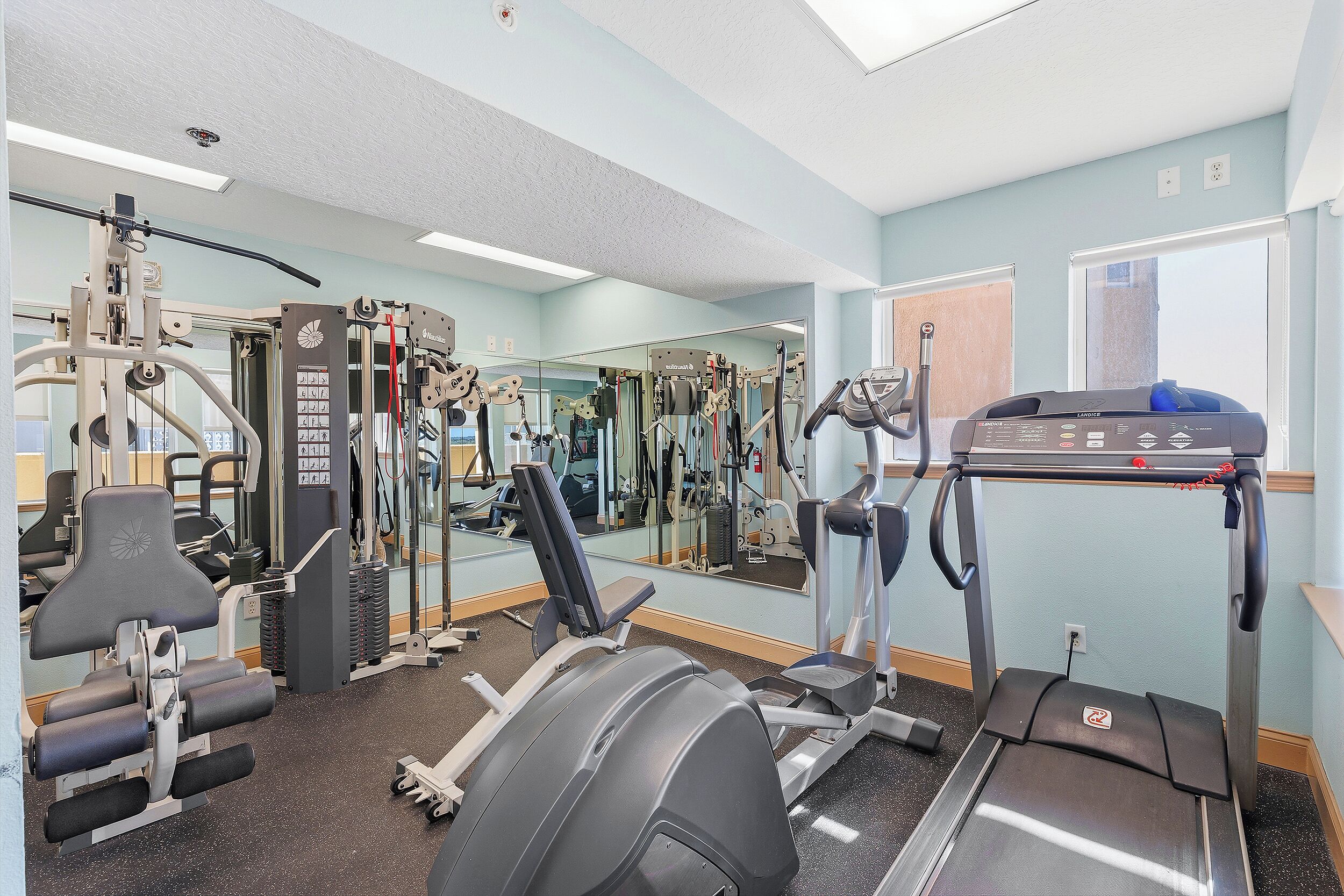 Un gimnasio con equipo de ejercicio, un espejo y una ventana.