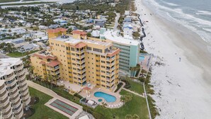 Vista aérea de un hotel costero con varias construcciones, una playa y un río.