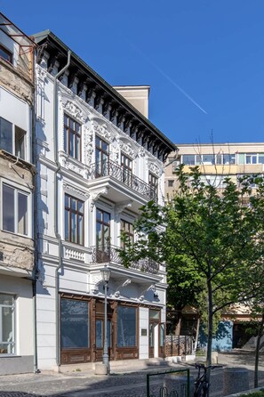 Ein mehrstöckiges Gebäude mit aufwendigen architektonischen Verzierungen, großen Fenstern und einem Balkon.