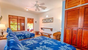 A room with two beds, a ceiling fan, wooden shutters, a small table, and a bench. - Bright and airy beachfront villa located in Soliman Bay with a New Pool (Tulum)