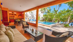 A spacious outdoor area with a pool, wicker furniture, and a dining area with a bar. - Bright and airy beachfront villa located in Soliman Bay with a New Pool (Tulum)
