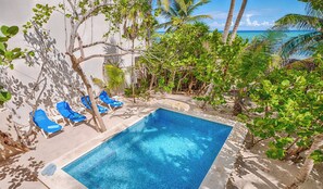 A pool area with blue chairs and a clear view of the ocean. - Bright and airy beachfront villa located in Soliman Bay with a New Pool (Tulum)