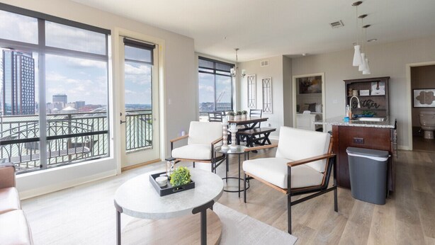 Un amplio espacio de sala con balcón, un comedor y una cocina.