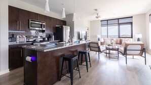 Una cocina moderna con armarios de madera oscura, electrodomésticos de acero inoxidable y una isla central con taburetes de bar.