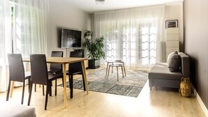 Ein modernes Wohnzimmer mit Essbereich, einer Couch, einem Fernseher und einer Pflanze.
