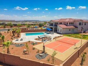 Un quartiere residenziale con piscina, campo da tennis e una grande casa con tetto rosso.