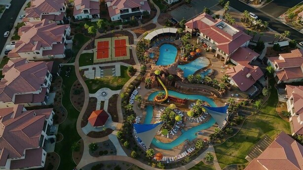 Oversigtsbillede af et resort med flere swimmingpools, en vandrutsjebane og en tennisbane.