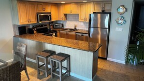 A modern kitchen with wooden cabinets, stainless steel appliances, and a granite countertop. - Beachfront! 3rd Floor Corner Unit, Enjoy Sunrise to Sunset (Stuart)
