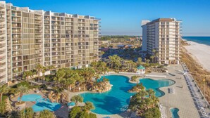 Un resort con múltiples edificios altos, un área de piscina central y vistas a la playa.