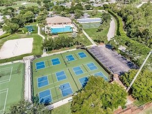 Vista aerea di un campo da golf con diversi campi da tennis, una piscina e vegetazione circostante.
