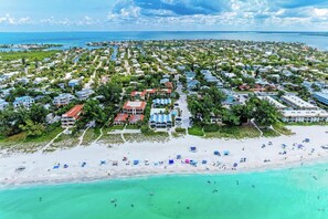 An aerial view of a coastal resort with beachfront properties, a sandy beach, and turquoise waters.