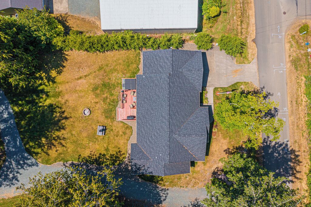 Vue aérienne d’un bâtiment doté d’un toit en pente, entouré de verdure et d’un espace de stationnement.