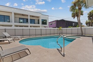 A swimming pool with a metal ladder, lounge chairs, and a white fence. - Beach Bungalow 1....Perfect duplex with shared pool (Fort Myers Beach)