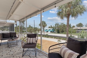 A covered outdoor seating area with wicker furniture and a patterned floor. - Beach Bungalow 1....Perfect duplex with shared pool (Fort Myers Beach)