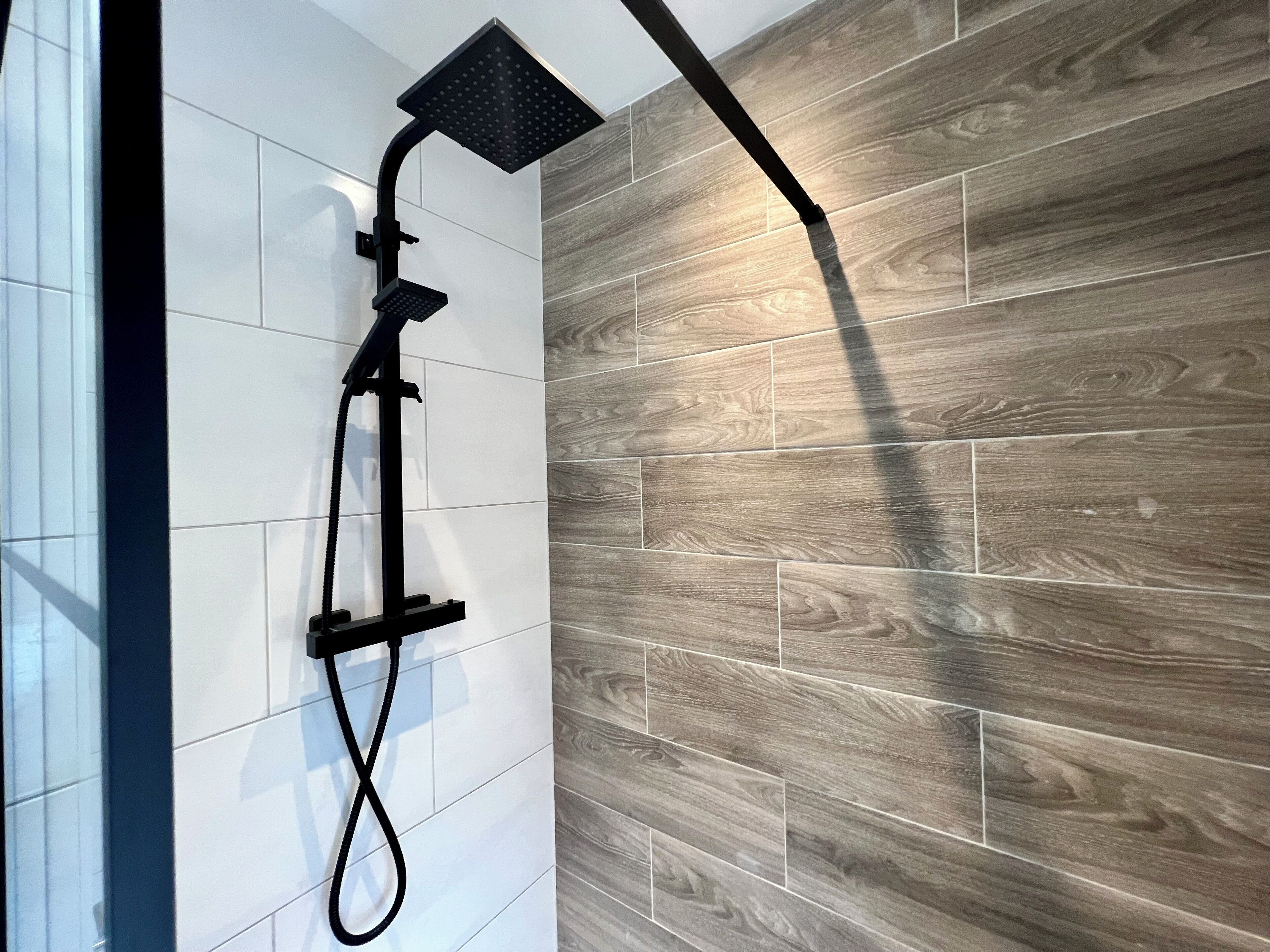 Une douche moderne dotée d’un pommeau noir et d’un flexible.