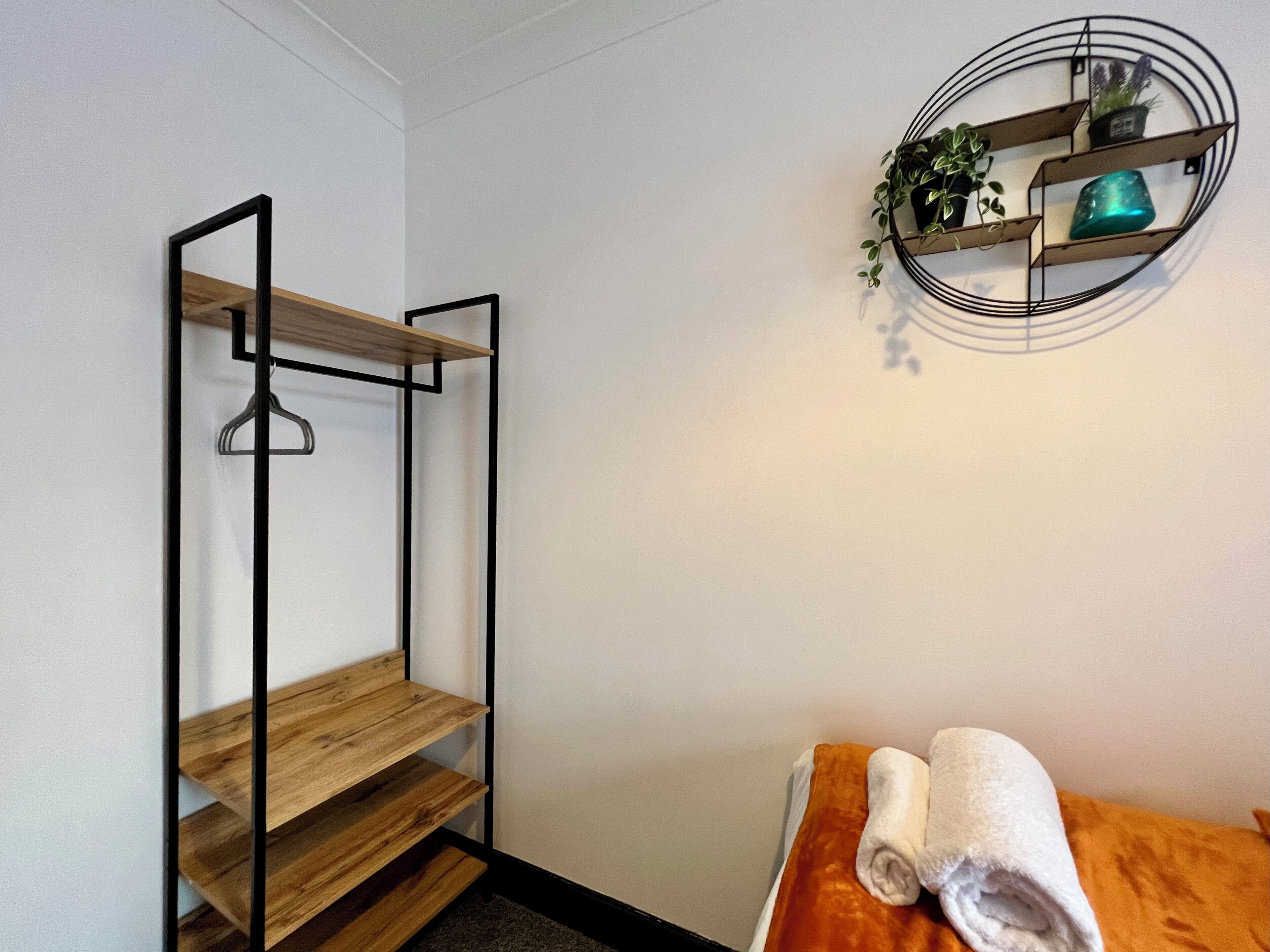 A room with a wooden shelf unit, a towel on a table, and a wall-mounted plant shelf.