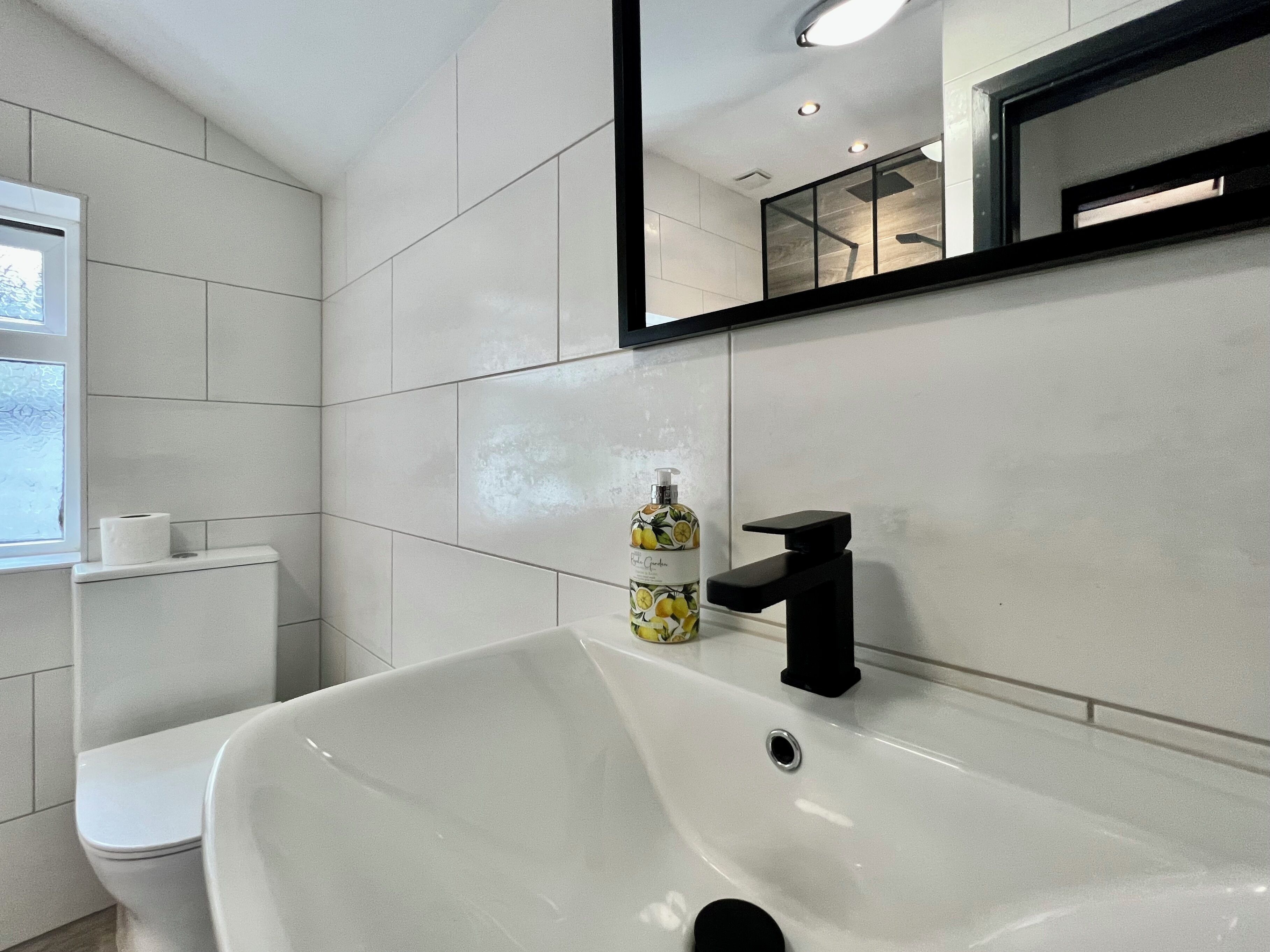 Une salle de bain moderne avec un lavabo blanc, des toilettes et un miroir.
