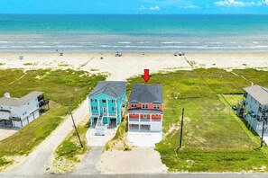 An aerial view of a coastal area with houses, a beach, and a road.