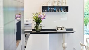 A modern kitchen with a black countertop, a vase with flowers, and a shelf with kitchenware.