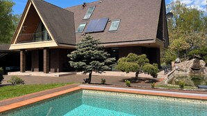A modern house with a swimming pool, solar panels, and a well-maintained garden.