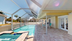 A covered outdoor swimming pool with a patio area, including seating and a door leading to a covered entryway. - House with Beach Access Point Just Around the Corner! (Marco Island)