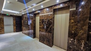 A modern elevator area with marble walls, a digital display, and a security notice. - Luxury 3-Bedroom Apartment at Eko Pearl, Eko Atlantic, Victoria Island, Lagos. (Lagos)