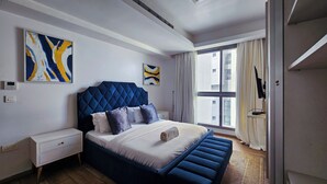 A modern bedroom with a large bed, a white nightstand, and a window with curtains. - Luxury 3-Bedroom Apartment at Eko Pearl, Eko Atlantic, Victoria Island, Lagos. (Lagos)