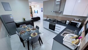 Et moderne køkken med spiseplads, udstyret med køleskab, komfur, mikrobølgeovn og vask.