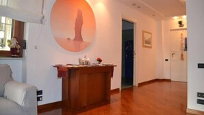A spacious room with a wooden floor, a round wall decoration, a wooden desk with a vase, and a door leading to another room. - Villa Regina Home - 120sqm, 3 bedrooms, 1 parking spot  (Boscoreale)