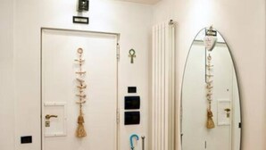 A hallway with a wooden floor, a white door with a keyhole, a radiator, and a large oval mirror on the wall. - Villa Regina Home - 120sqm, 3 bedrooms, 1 parking spot  (Boscoreale)