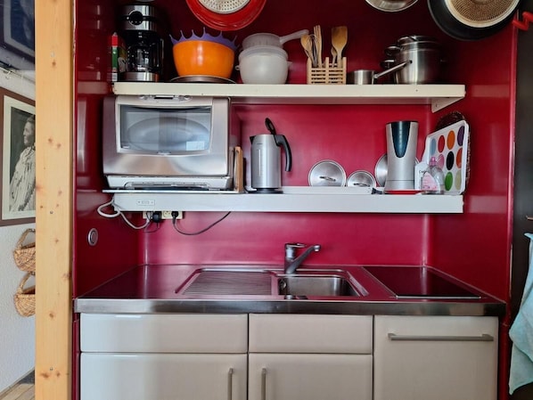 Une cuisine compacte équipée d’un four à micro-ondes, d’un grille-pain et d’un évier.
