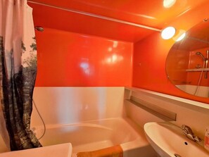 Une salle de bain avec une baignoire, un lavabo et un miroir.