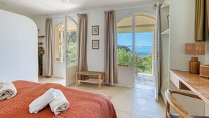 Une chambre avec un lit, une chaise, un bureau et une vue sur la mer.