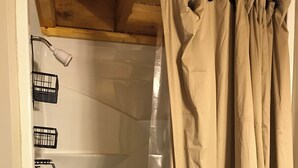 A shower area with a glass door, a white bathtub, and a beige shower curtain. - Judy's Place - 1BR, 1 Bath w/ Q, K, and Twin bed. Full kitchen. (Putney)
