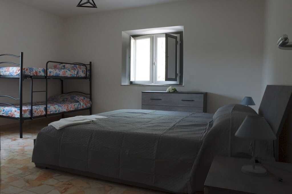 Ein Schlafzimmer mit Etagenbett, einem Einzelbett, einem Schminktisch und einem Spiegel sowie einem Fenster.