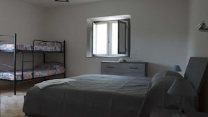 Un dormitorio con una cama litera, una cama individual, un aparador, un espejo y una ventana.