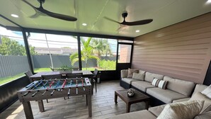 Eine geräumige Terrasse mit Tischfußball, einer Sitzecke und einem Deckenventilator.