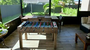 Ein großzügiger Patio-Bereich mit Kicker, bequemen Sitzgelegenheiten und Blick zum Garten.