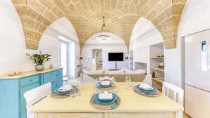 Un espace repas doté d’un plafond en pierre, de murs blancs et d’un téléviseur fixé au mur.