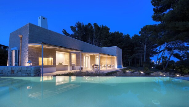 Une maison moderne dotée d’une piscine, de murs en pierre et d’un espace patio.