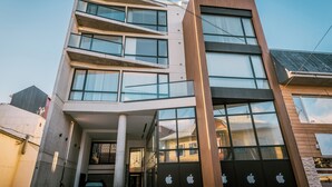 Un edificio moderno con varios pisos, ventanas amplias y un logotipo de Apple destacado en la fachada.