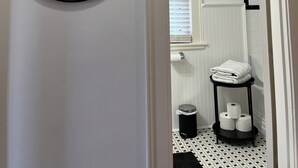 A bathroom with a white wall, a round mirror, a toilet paper holder, and a trash can. - Great 3BR home in Lynchburg, great location near colleges, great amenities (Lynchburg)