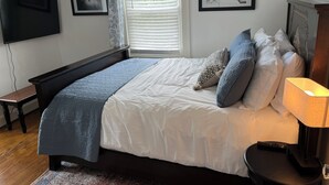 A bedroom with a bed, a TV, a window with blinds, and two framed pictures on the wall. - Great 3BR home in Lynchburg, great location near colleges, great amenities (Lynchburg)