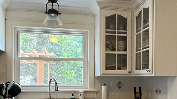 A kitchen with white cabinets, a black countertop, a window with a view of greenery, and a ceiling light fixture. - Great 3BR home in Lynchburg, great location near colleges, great amenities (Lynchburg)