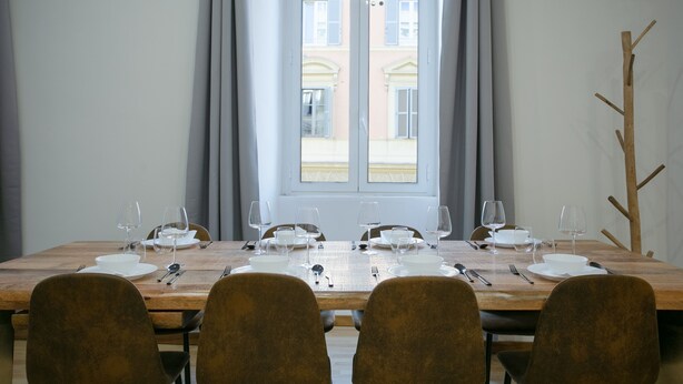 A dining table set for six with chairs, a window with curtains, and a view of buildings outside. - APT Rome 5 BDRM’s (Roma)