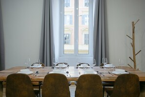 A dining table set for six with chairs, a window with curtains, and a view of buildings outside. - APT Rome 5 BDRM’s (Roma)